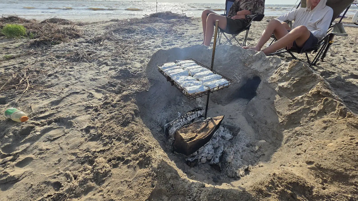 Family in camp chairs around the Tyrux Campfire Grill over a beach fire pit