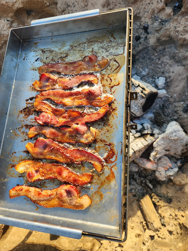 Bacon cooking on the Tyrux Griddle Pan Insert in the Tyrux Campfire Grill